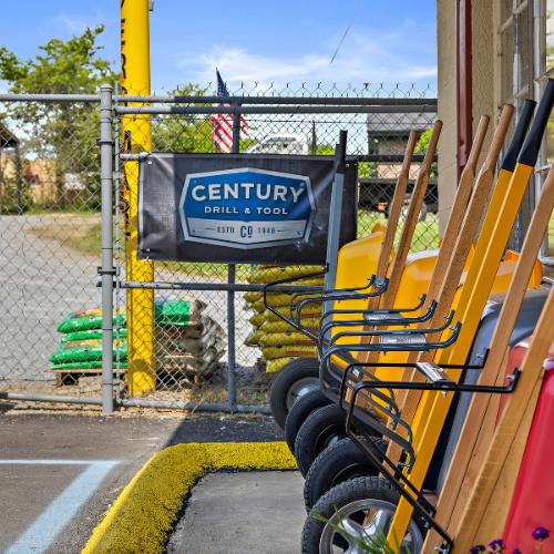 A Century Drill & Tool sign outside our store, with wheelbarrows in the forefront on the right side.