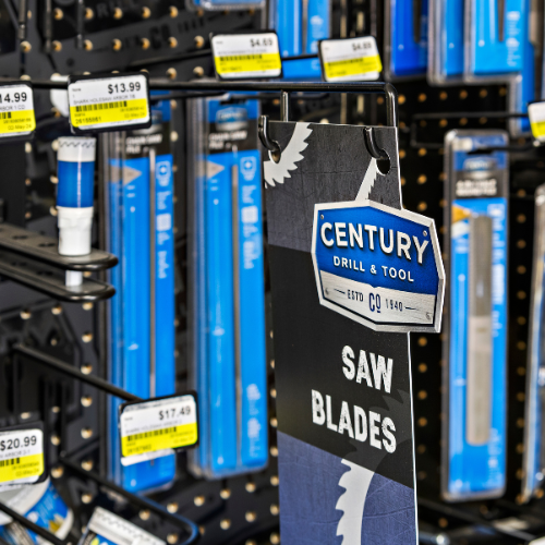 Century Drill & Tool saw blade sign in the forefront with blurred saw blades in the background.