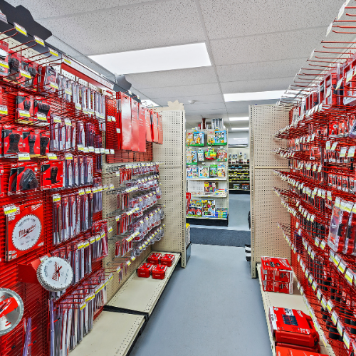 An aisle filled with Milwaukee tools and accessories, including saw blades, drill bits, drills, and more. The shelves have a Milwaukee red background.