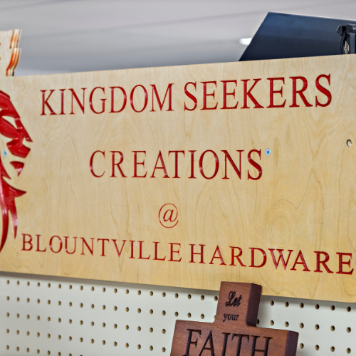 A wooden Kingdom Seekers Creation sign hanging on a shelf.